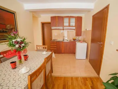 a kitchen with a table and a white refrigerator at Villa INA in Kaluđerac