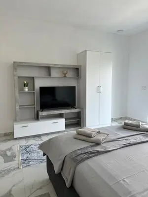 a white bedroom with a large bed and a flat screen tv at Alfredo in Ulcinj