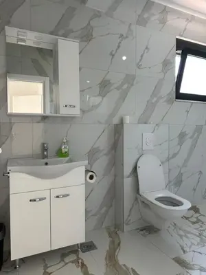 a white bathroom with a toilet and a sink at Alfredo in Ulcinj