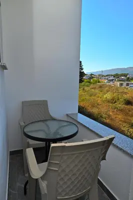 a table and a chair on a balcony with a window at Stars Five Apartments in Ulcinj