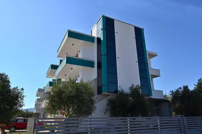 a tall white building with green windows at Stars Five Apartments in Ulcinj