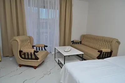a hotel room with a bed and chairs and a table at Stars Five Apartments in Ulcinj