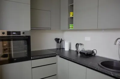 a kitchen with white cabinets and black counter tops at Urban Nest - New City in Podgorica