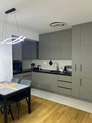 a kitchen with white cabinets and a dining table at Urban Nest - New City in Podgorica