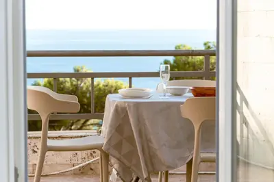 a table with a glass of wine on a balcony at Peaceful Sea View Apartment in Bar