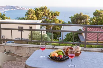 a table with a bowl of fruit and two glasses of wine at Peaceful Sea View Apartment in Bar