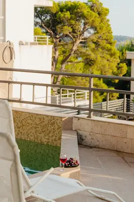 a glass of wine and a bowl of fruit on a balcony at Sea View Retreat with Pool in Bar