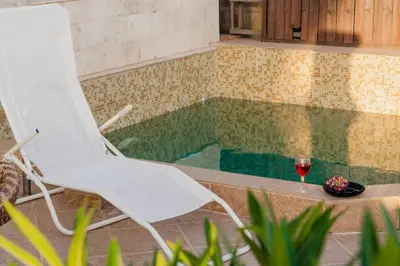 a white chair and a glass of wine next to a pool at Sea View Retreat with Pool in Bar