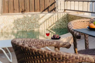a table with a glass of wine on a patio at Sea View Retreat with Pool in Bar