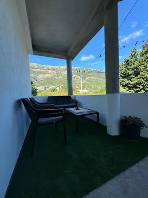 a balcony with a table and a chair on the grass at Apartmani Đurović - Sutomore in Bar