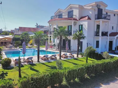 a large white house with a swimming pool and palm trees at Apartments Lj in Ulcinj