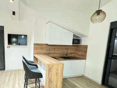 a kitchen with white cabinets and a black chair at Apartments Lj in Ulcinj