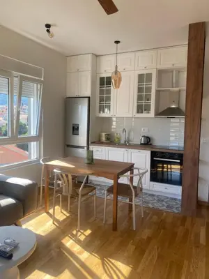 a kitchen with a wooden table and a kitchen with white cabinets at Comfort Stylish Apartment IVSOLE in Budva
