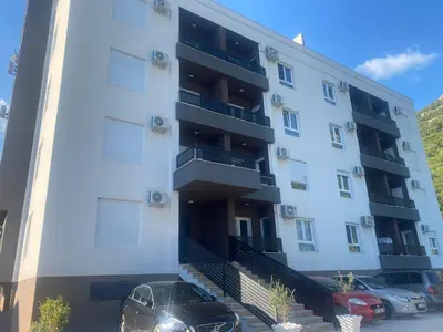 a building with a car parked in front of it at Comfort Stylish Apartment IVSOLE in Budva