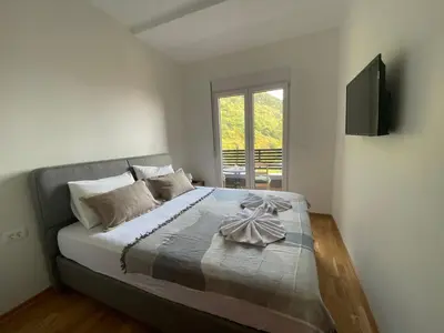 a bedroom with a bed with a television on the wall at Comfort Stylish Apartment IVSOLE in Budva