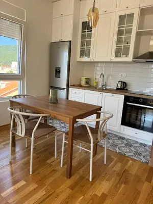 a kitchen with a wooden table and a refrigerator at Comfort Stylish Apartment IVSOLE in Budva