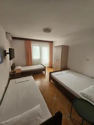 a bedroom with two beds and a table and a window at Apartment Aleksic Becici in Becici