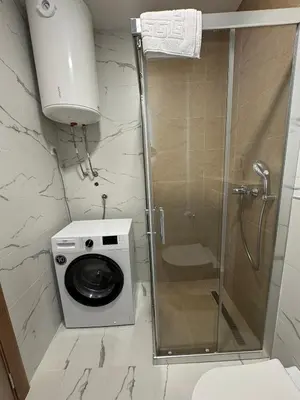 a bathroom with a shower and a washing machine at Stylish Studio IVSOLE in Budva