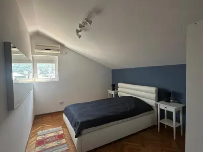 a bedroom with a bed and a blue accent wall at Stunning view designer apartment in Budva