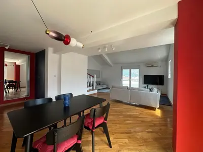 a dining room and living room with a table and chairs at Stunning view designer apartment in Budva