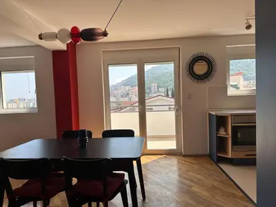 a dining room with a table and chairs and a window at Stunning view designer apartment in Budva