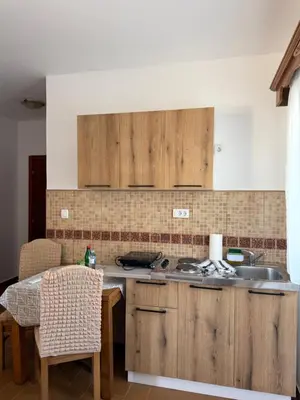 a kitchen with wooden cabinets and a sink and a table at Monte Lastva Apartments in Podlastva