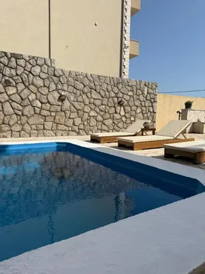 a swimming pool in front of a building with a stone wall at Monte Lastva Apartments in Podlastva