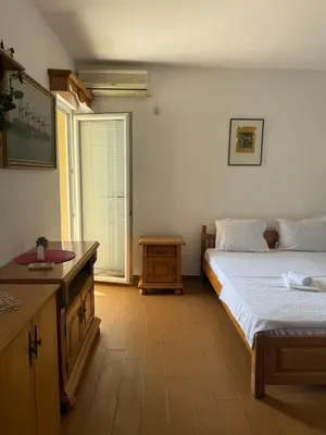 a bedroom with two beds and a table and a window at Monte Lastva Apartments in Podlastva
