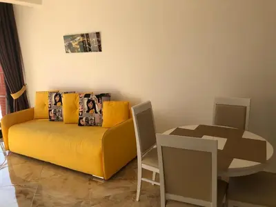 a living room with a yellow couch and a table at Seaview apartment in Dobra Voda