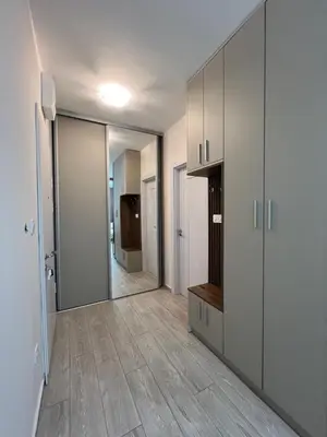 a room with a hallway with white cabinets and wood floors at FAB LIFE Becici in Becici