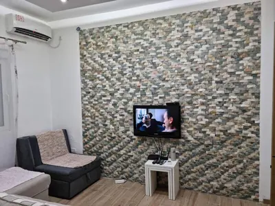 a living room with a tv on a brick wall at Apartman Duki in Budva