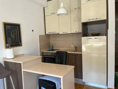 a small kitchen with a refrigerator and a table at Apartman Mega Budva in Budva