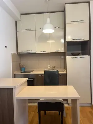 a kitchen with a table and a black chair at Apartman Mega Budva in Budva