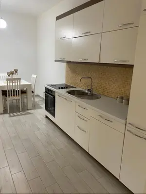 a kitchen with white cabinets and a sink and a table at I&A Apartments in Ulcinj