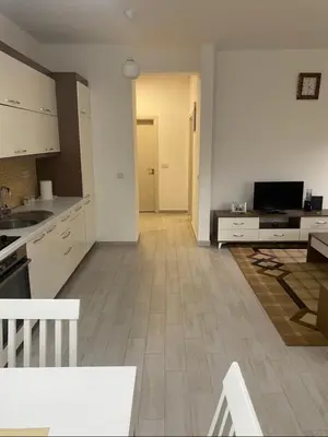 a kitchen with white cabinets and a living room at I&A Apartments in Ulcinj
