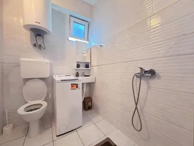 a white bathroom with a toilet and a shower at Sunny Nest Studio Bar in Bar
