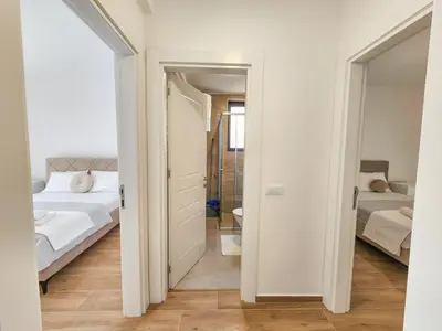 a white bedroom with a bed and a bathroom at Tarik Apartment in Ulcinj