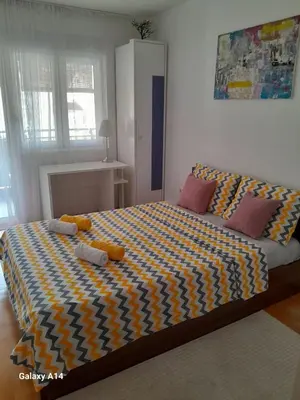 a bedroom with a large bed with a yellow and blue blanket at Apartman Ana in Budva