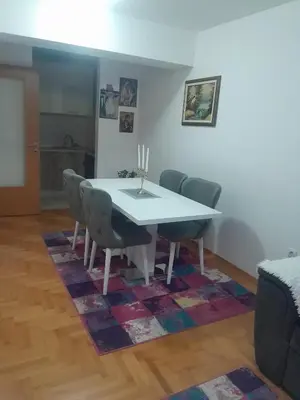 a dining room with a table and chairs on a rug at Apartman Ana in Budva