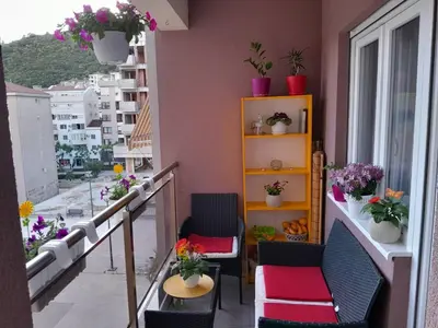 a balcony with chairs and a shelf with potted plants at Apartman Ana in Budva