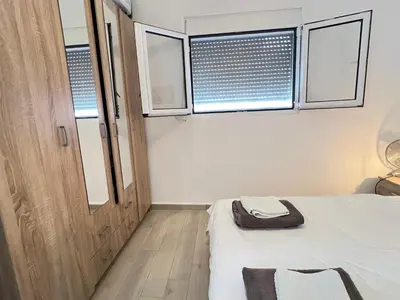 a small bedroom with a bed and two windows at Second floor near the Long Beach, Montenegro in Ulcinj
