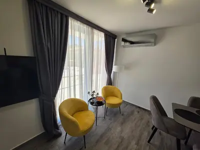 a living room with yellow chairs and a table and a window at Villa Azzurra in Radanovići