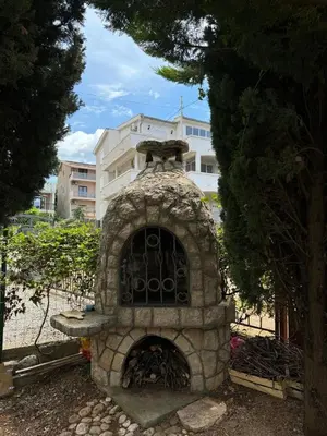a stone fireplace in front of a building at Apartments Sava in Dobra Voda
