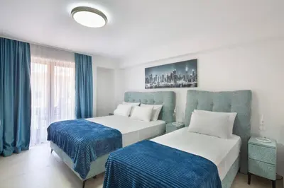 two beds in a hotel room with blue curtains at Residence Tommy in Budva