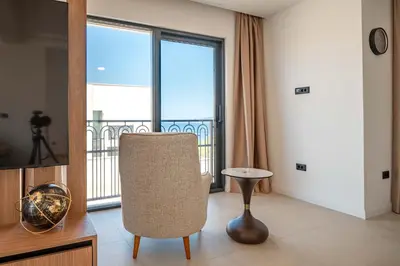 a living room with a chair and a balcony at Luxury Villa - New Building with pool and Fantastic Side Sea View in Budva