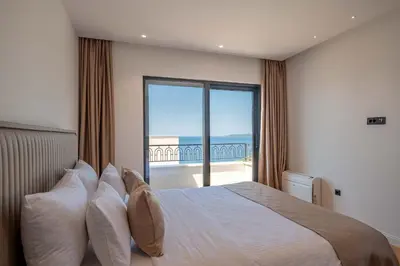 a bedroom with a bed with a view of the ocean at Luxury Villa - New Building with pool and Fantastic Side Sea View in Budva