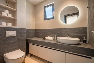 a bathroom with a sink and a toilet and a mirror at Luxury Villa - New Building with pool and Fantastic Side Sea View in Budva