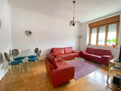 a living room with a red couch and a table at Heart of the city big 1BR on Independence square in Podgorica