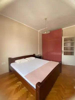 a bedroom with a large bed with a red door at Heart of the city big 1BR on Independence square in Podgorica