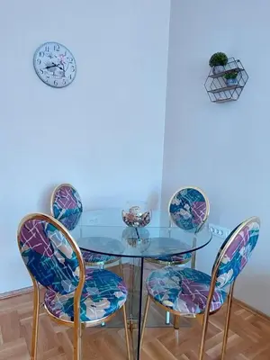 a glass table with four chairs and a clock on the wall at Heart of the city big 1BR on Independence square in Podgorica